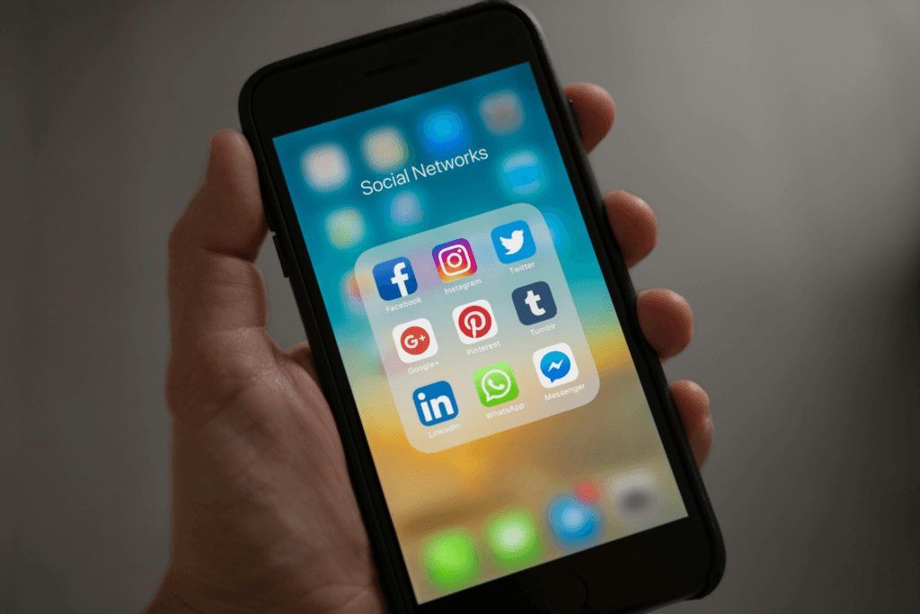 Ruka držící mobil na kterém jsou zobrazeny ikony sociálních sítí