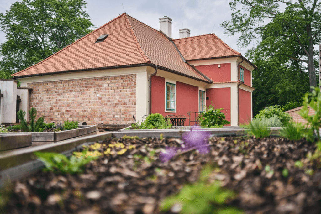 Domek u tzv. červené brány zobrazen s bylinkovou zahrádkou.