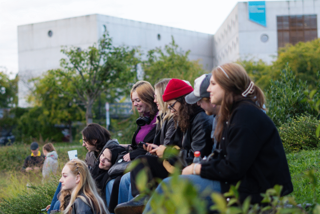 Diskutující studenti sedící v parku.