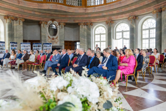 Lidé sedící v zámeckém sále.